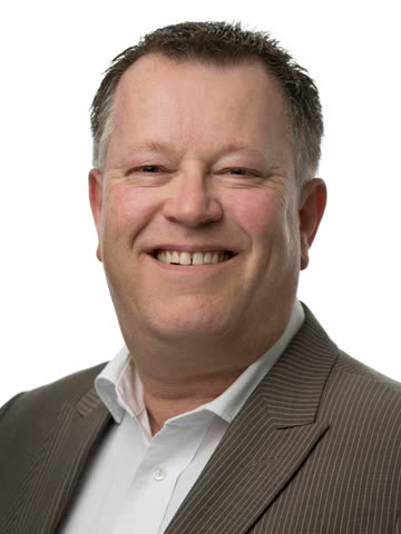 Portret van Ton Houtenbos, lachend, in een gestreept colbert met wit overhemd