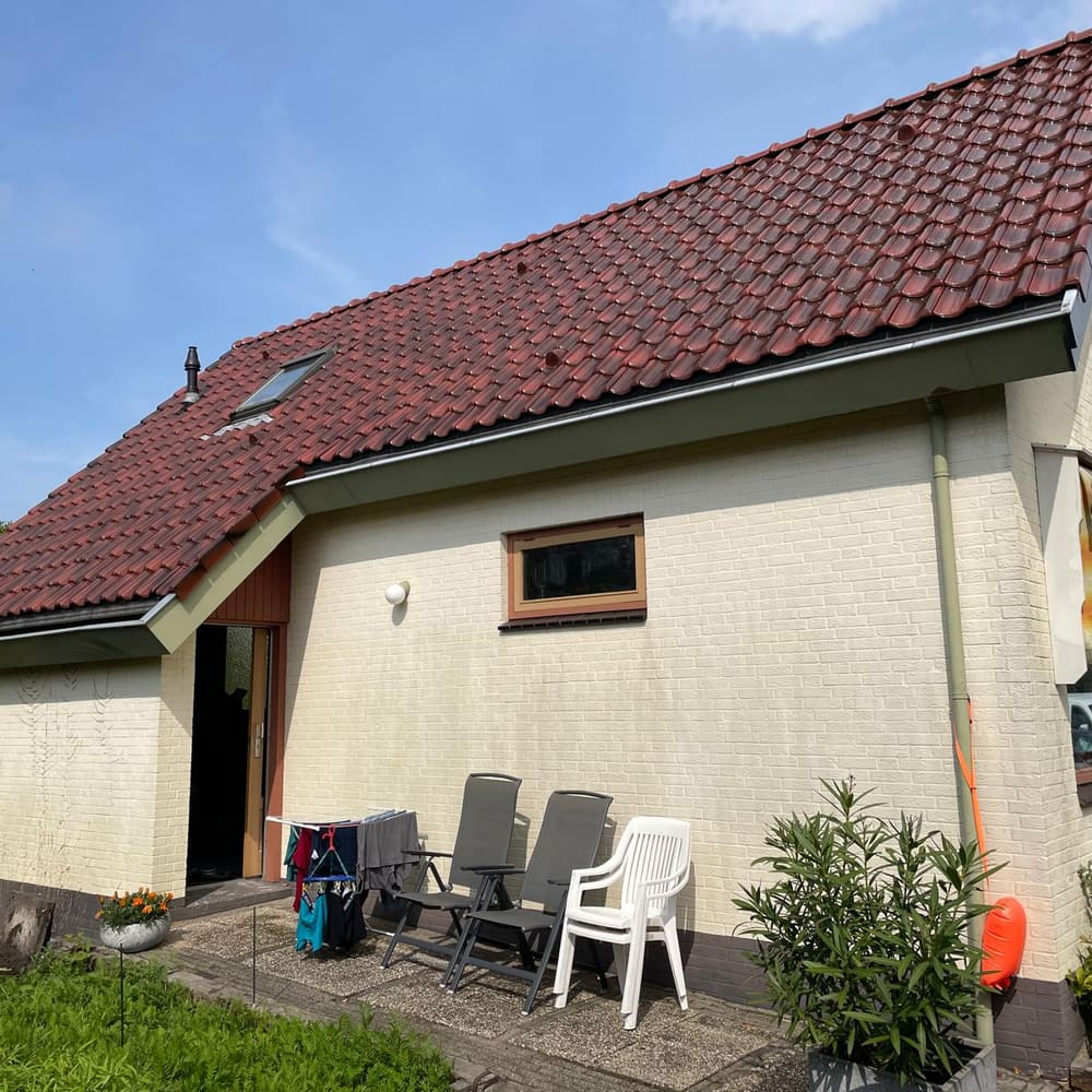 Dezelfde woning aan de tuinzijde, met een breed pannendak, een dakraam en een terras