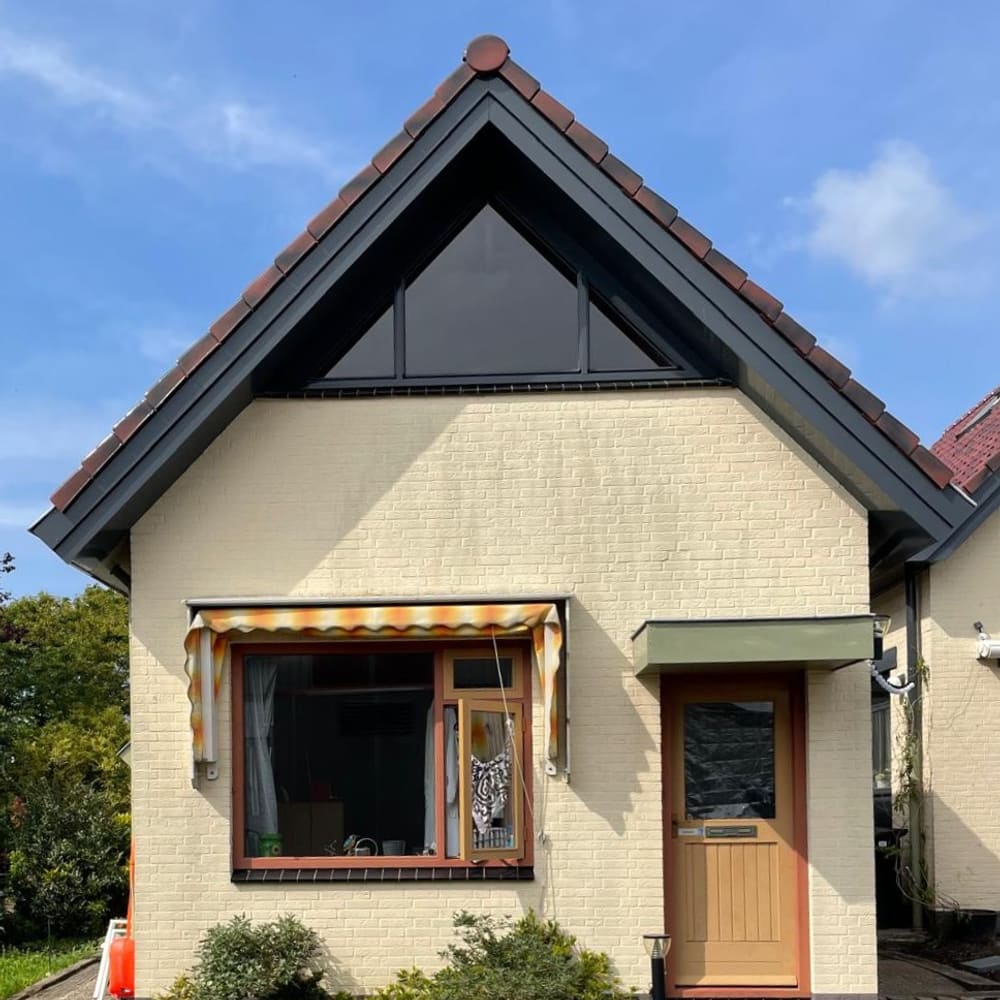 Vrijstaande woning met cr&egrave;mekleurige baksteen, rode dakpannen en een driehoekig raam in de topgevel